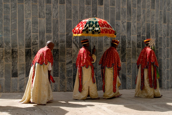 Ethiopian Orthodox procession of priests holding a colourful umbrella walking around the New Cathedral of Axum,Ethiopia,